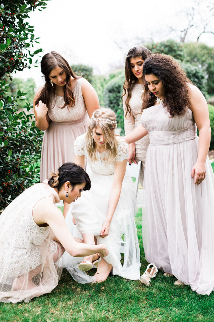 bridesmaids helping bride put on shoes