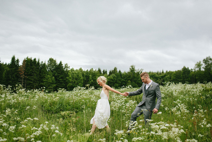 bride and groom walking through meadow