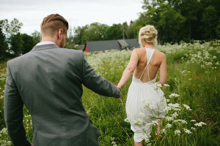 bride and groom walking through meadow