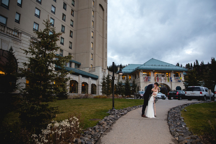 bride and groom kissing in front of hotel