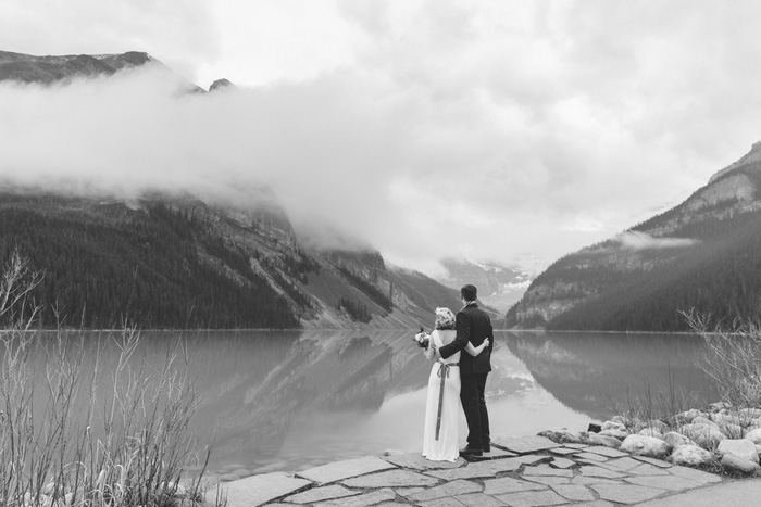 bride and groom looking out over Lake Louise