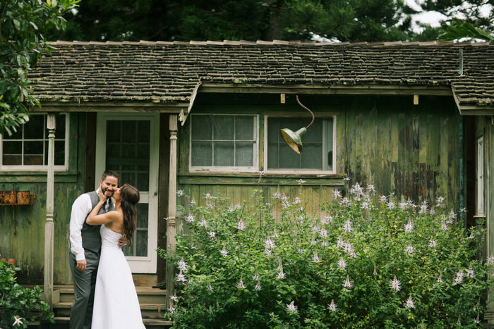 bride kissing groom in front of cottage