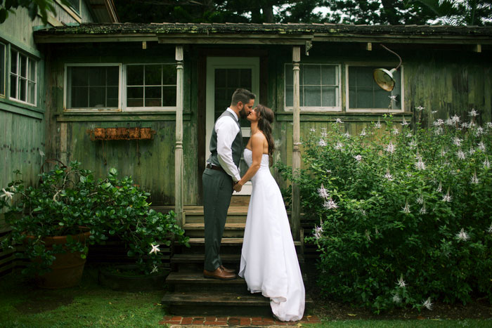 bride and groom kissing outside cottage