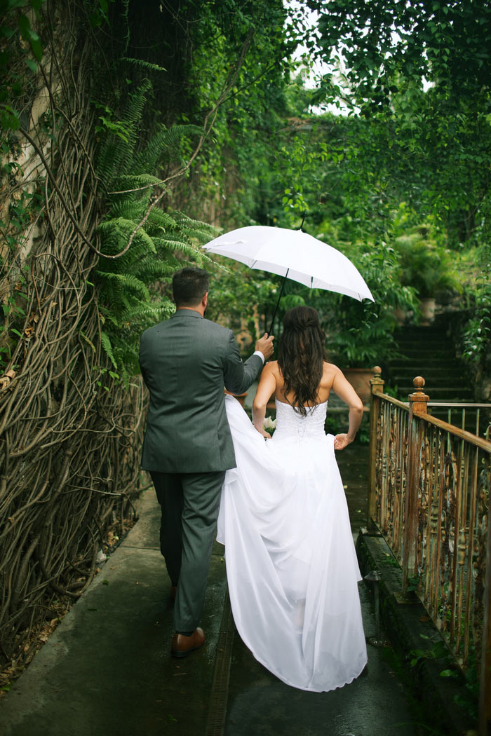 bride and groom walking under umbrella