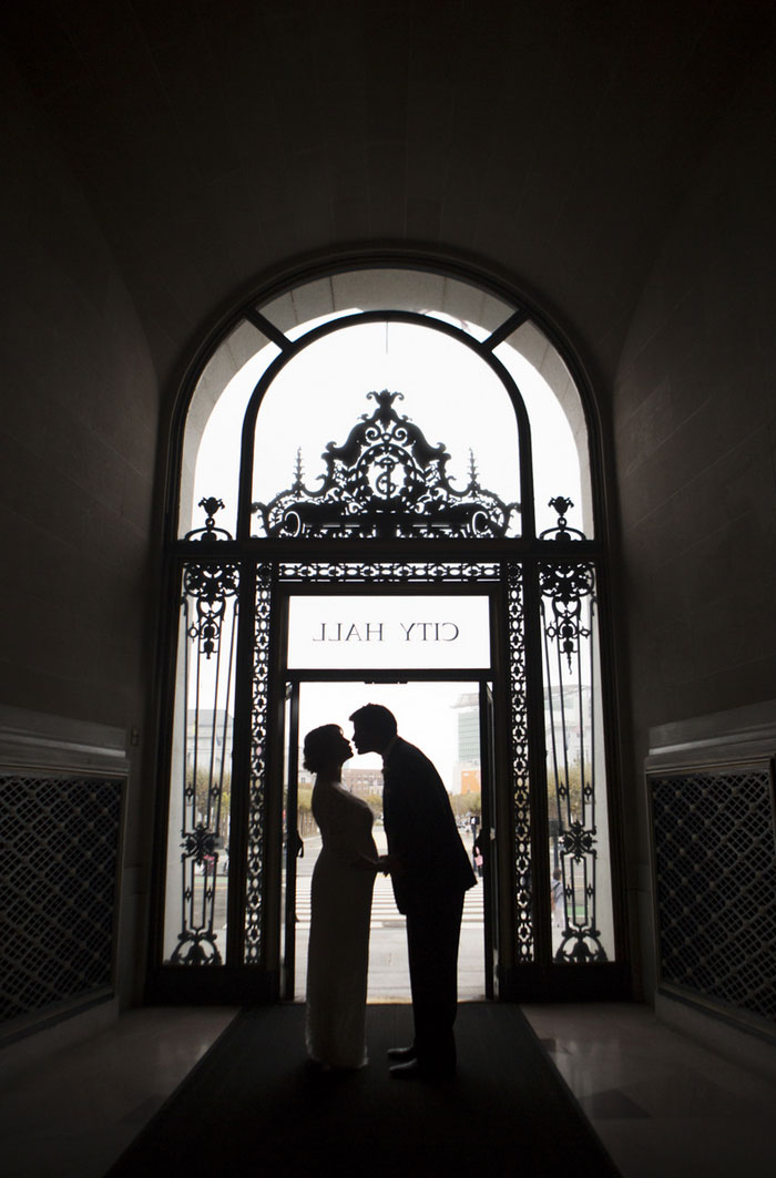 bride and groom kissing in city hall doorway