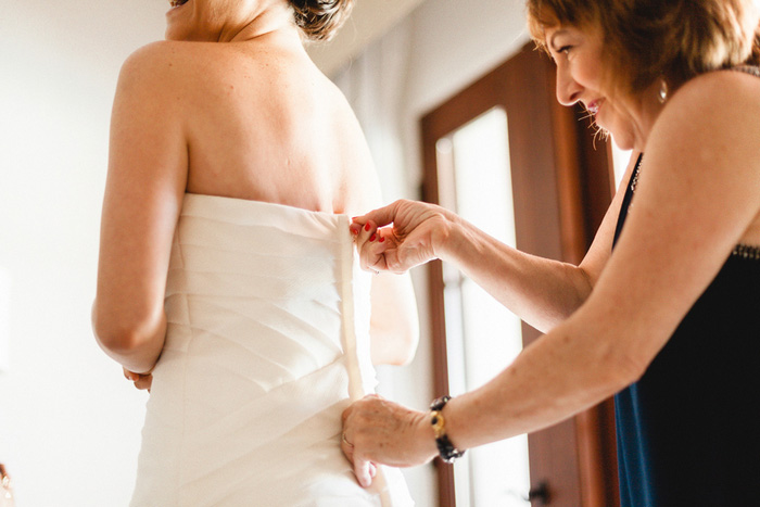 bride getting her dress zipped up