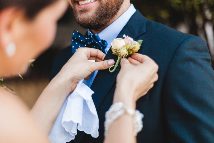 groom having boutonniere pinned on 