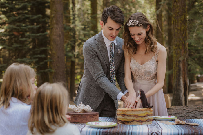 bride and groom cutting cake in the woods