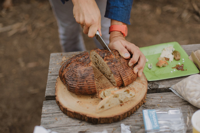 wedding guest slicing bread in the woods