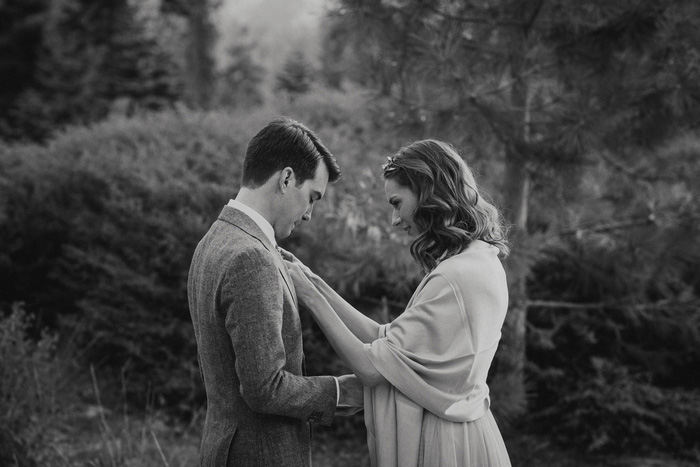 bride pining boutonniere on groom 