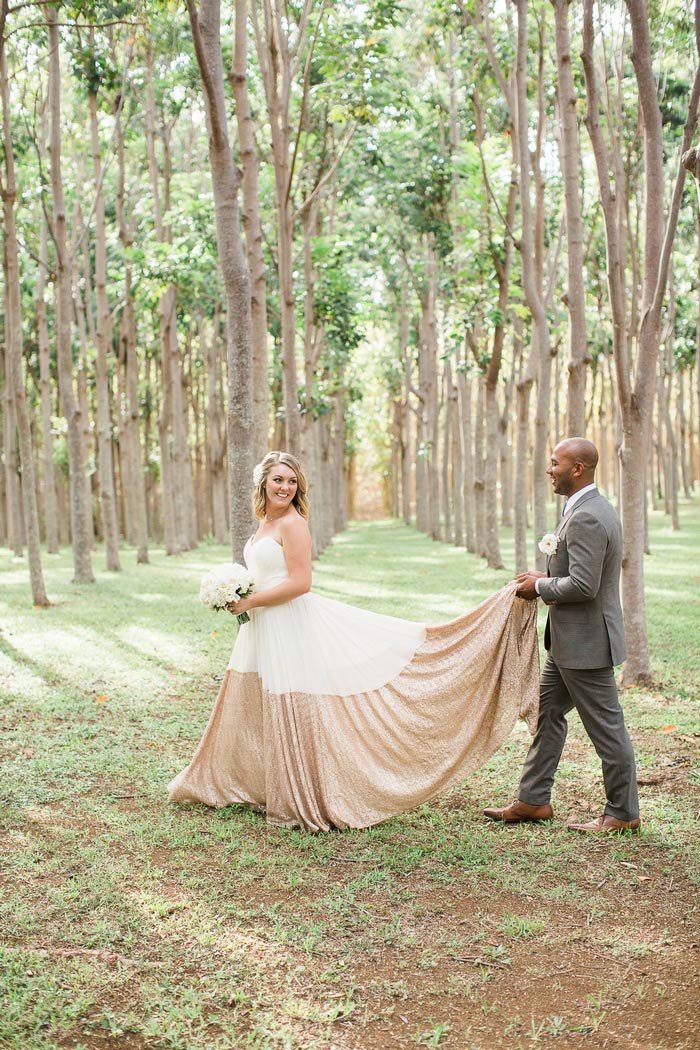 groom holding up bride's train as they walk