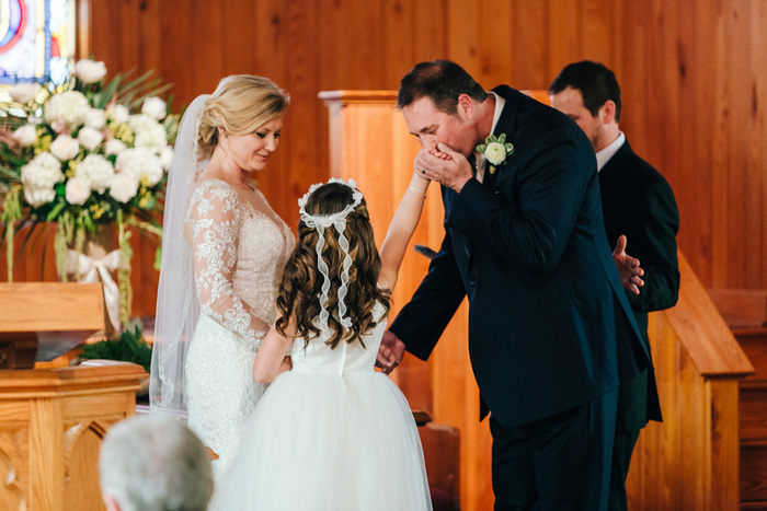 groom kissing flower girl's hand