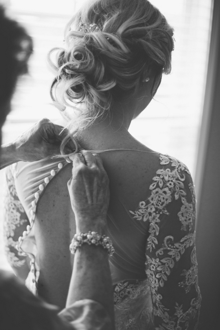 bride having her dress buttoned up the back