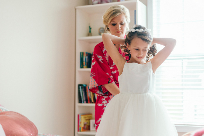 bride helping flower girl get dressed