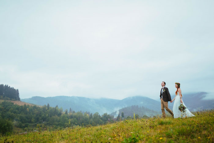 bride and groom walking on hill