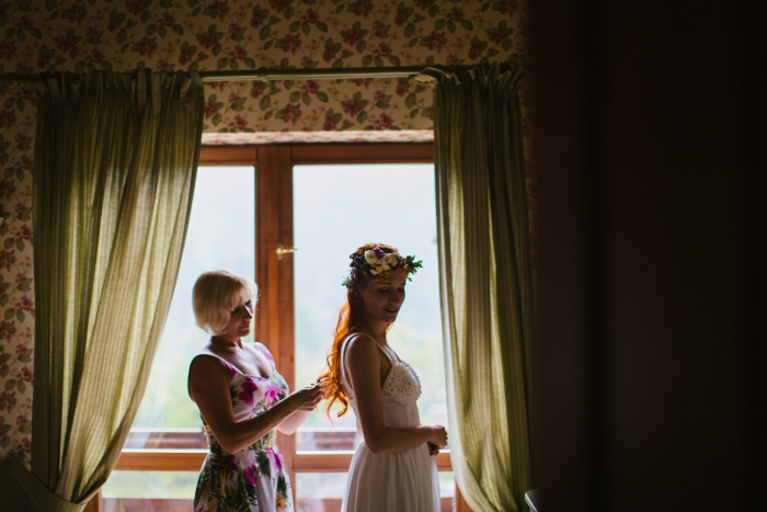 bride getting zipped into her wedding dress