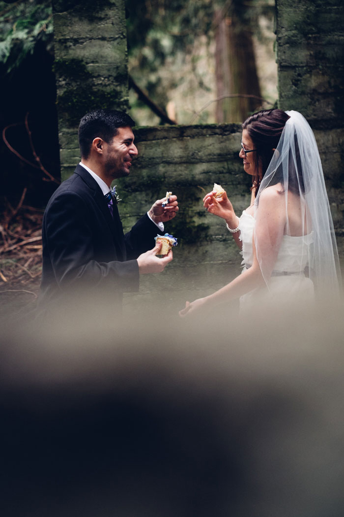 bride and groom eating cake in the woods