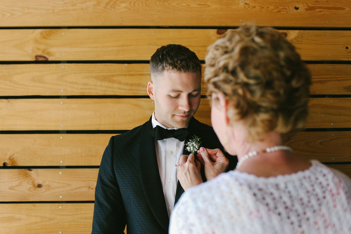 groom having boutonnière pinned on