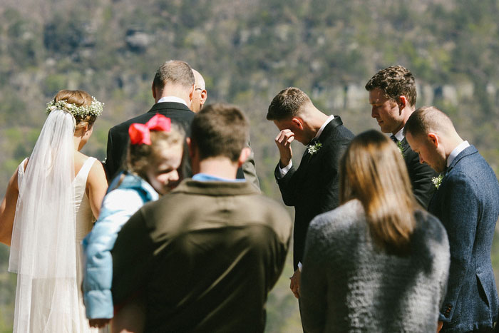 groom wiping away tears as bride walks down the aisle