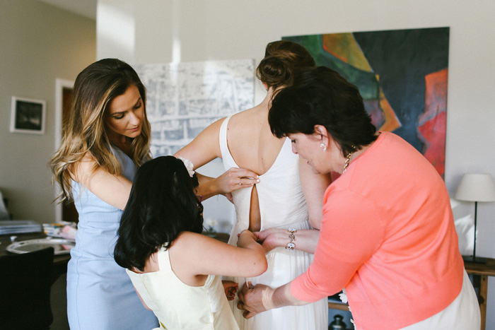 bride being zipped into dress