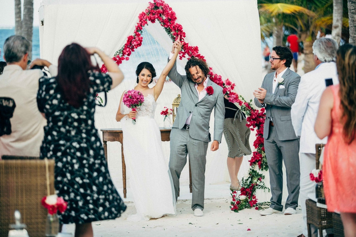 bride and groom raising arms in victory