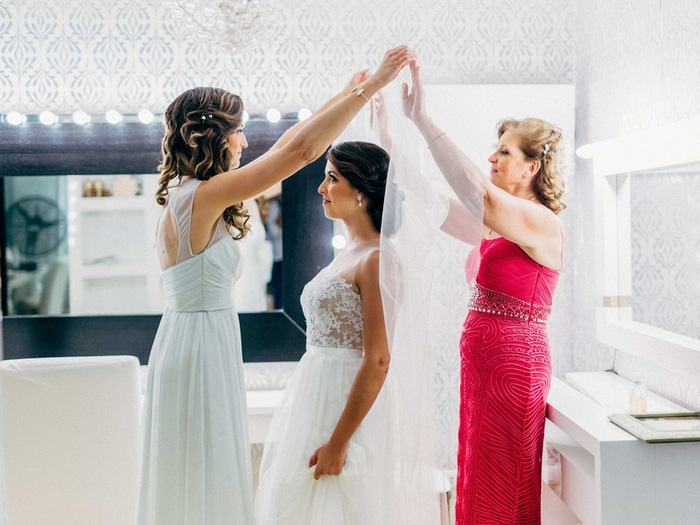 bridesmaids putting bride's veil on