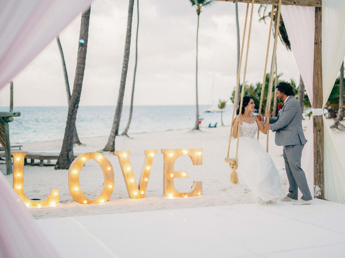 bride and groom portrait on the beach with love sign