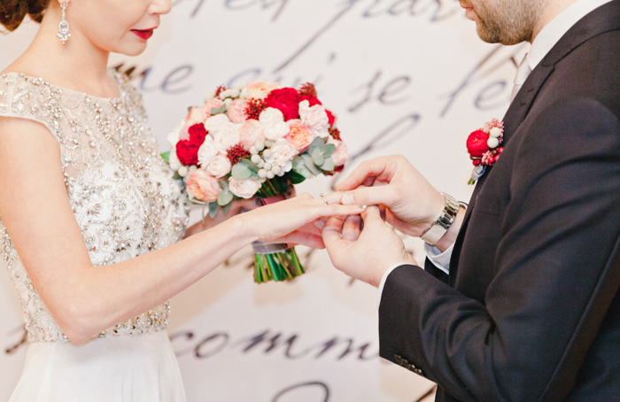 groom putting ring on bride's finger