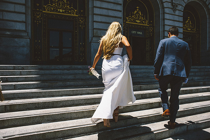 bride and groom walking up steps of San Francisco City Hall