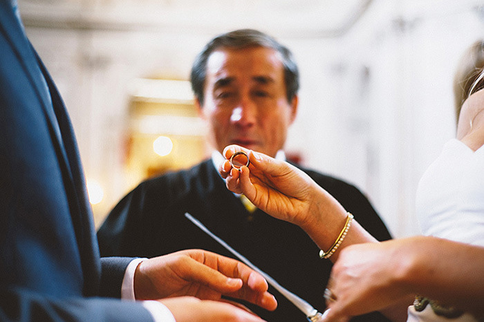 bride holding up ring during ceremony