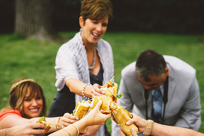 wedding guests toasting with sandwiches in the park