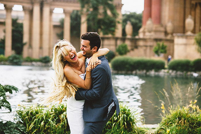 bride laughing while dancing with groom in the park