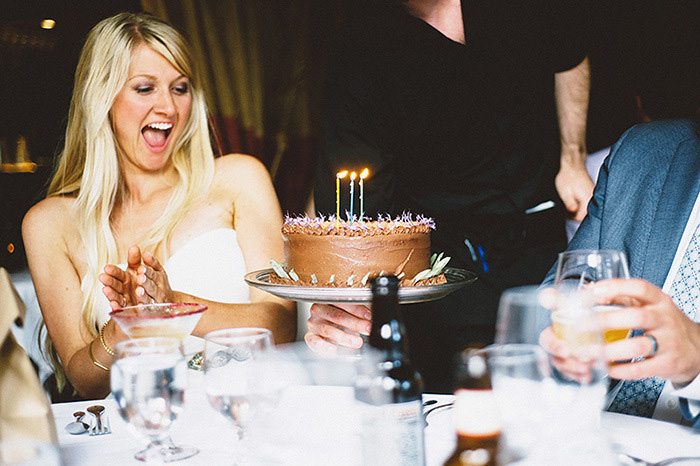 chocolate wedding cake with candles being brought out to bride and groom