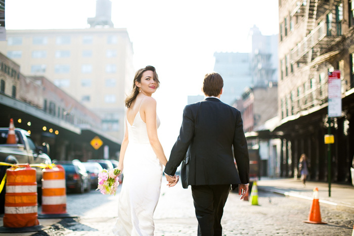 bride looking over shoulder while walking with groom