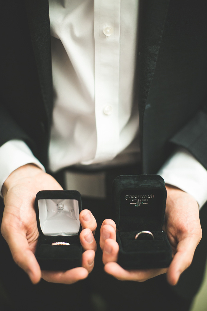 groom holding wedding rings