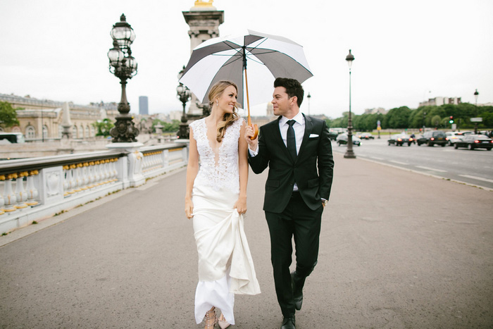 bride and groom walking under umbrella