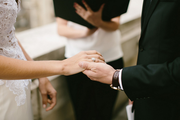 groom holding bride's hand during ceremony