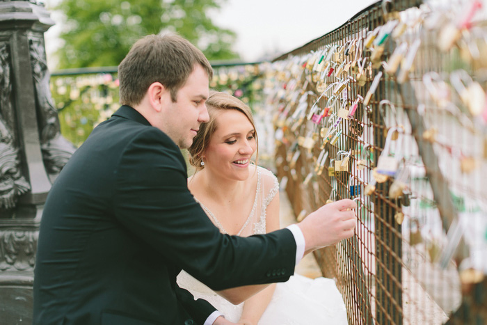 bride and groom putting lock on bridge