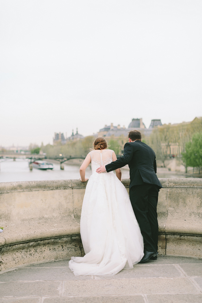 bride and groom looking over bridge into the seine