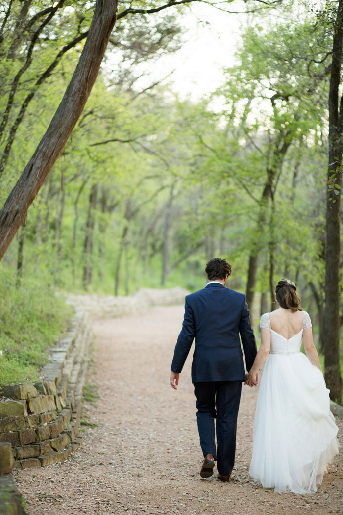 bride and groom walking down wooded path