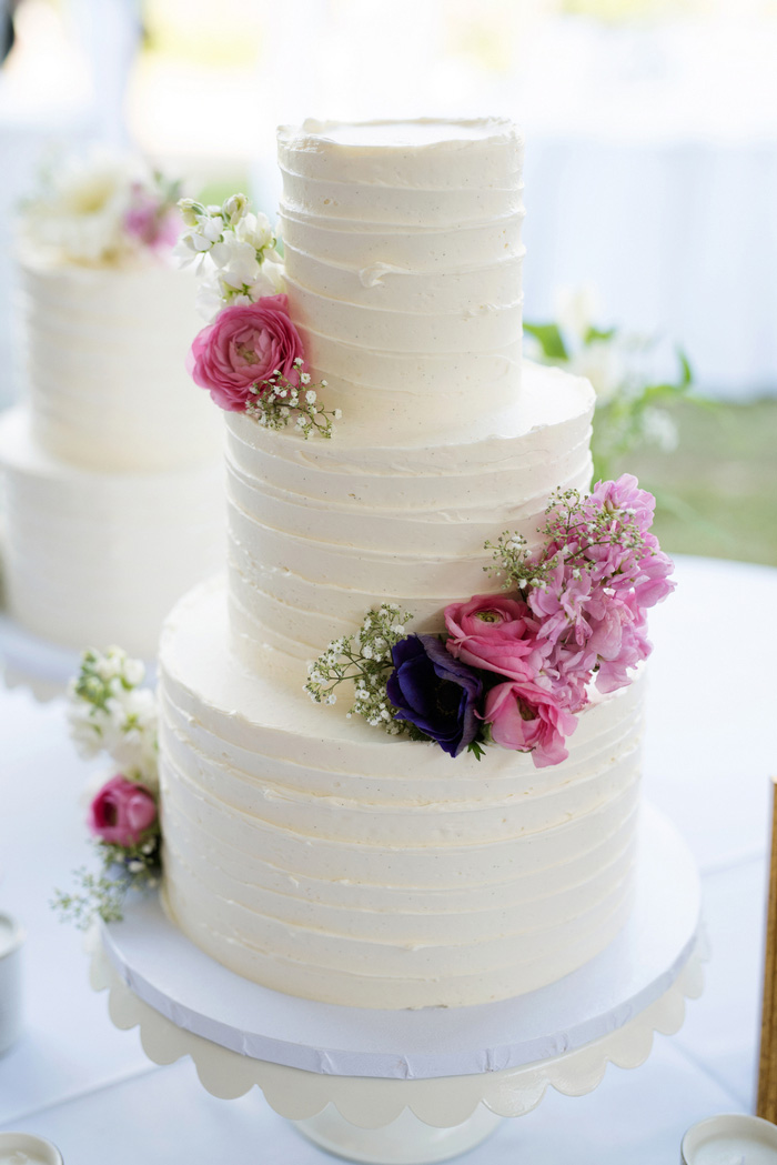 3 tiered white wedding cake with fresh pink flowers