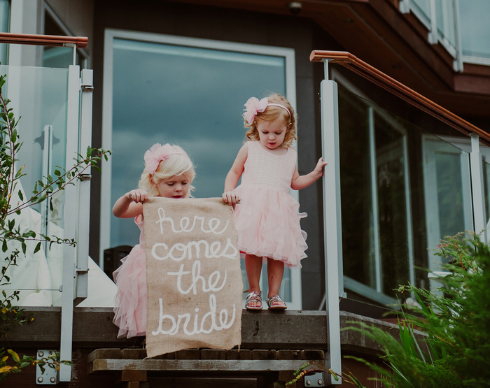 flower girls holding here comes the bride sign