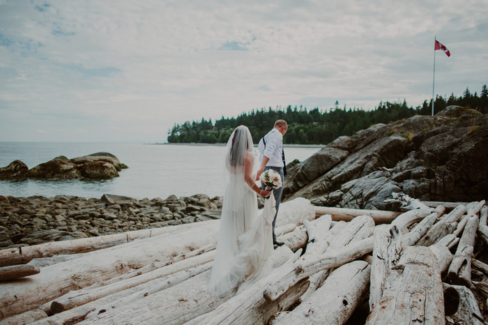 bride and groom walking on rocky beach