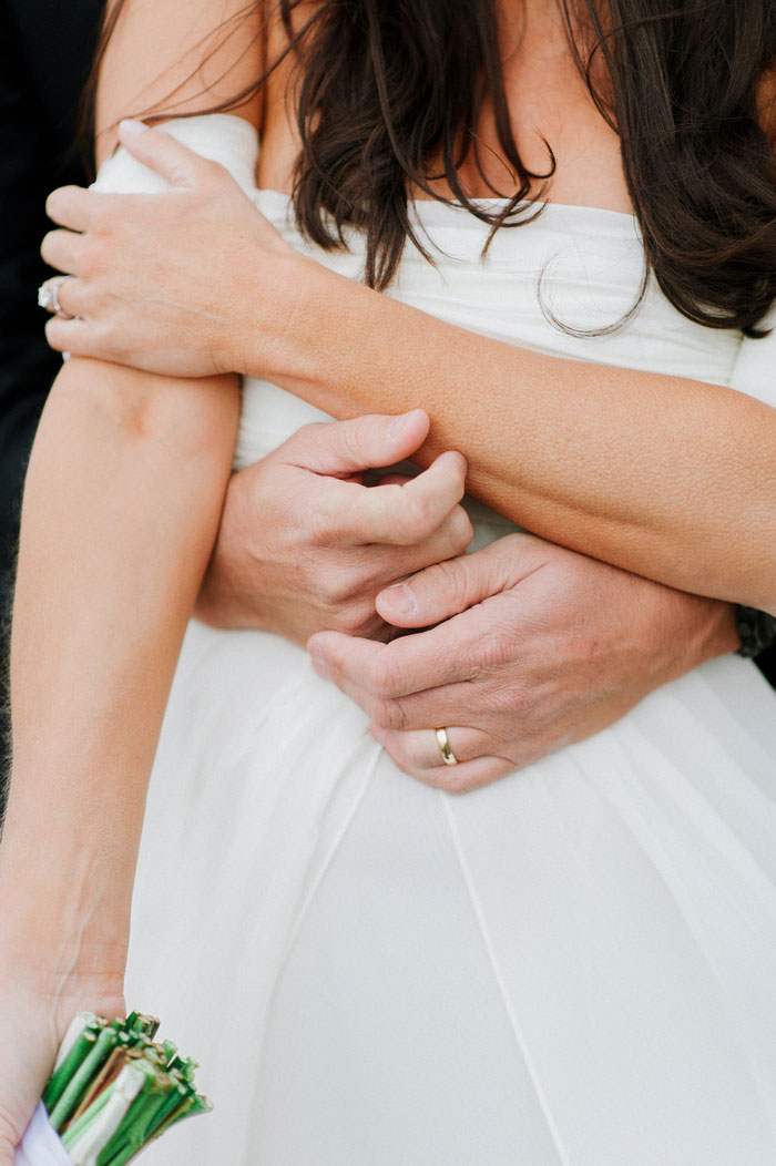 bride with groom's arms wrapped around her