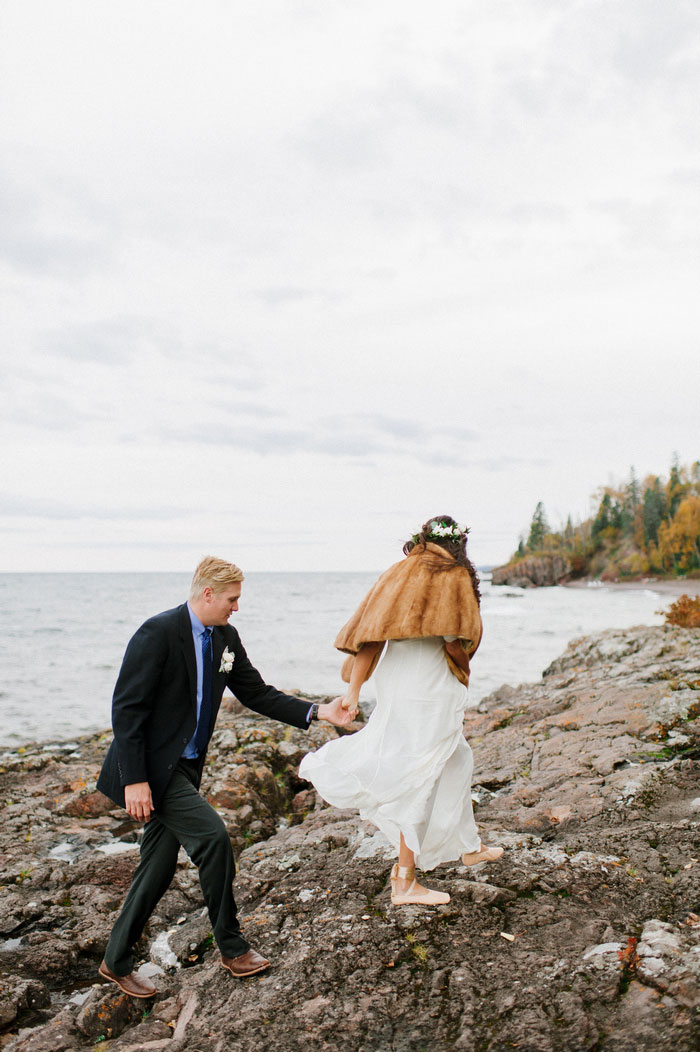 bride and groom walking on rocky beach