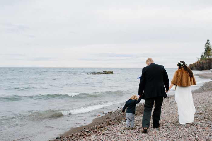 bride, groom, and son walking on the beach