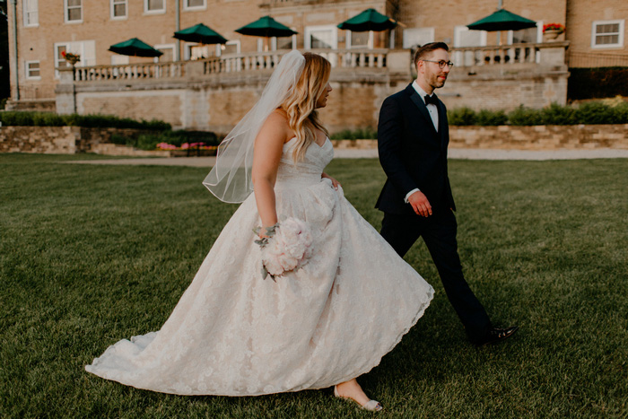 bride and groom walking across estate lawn