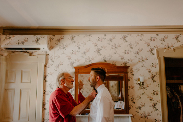 groom having bow tie tied