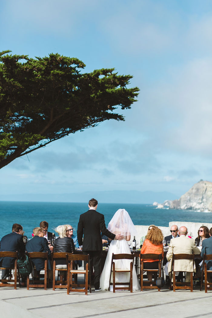 bride and groom from behind standing at dinner table