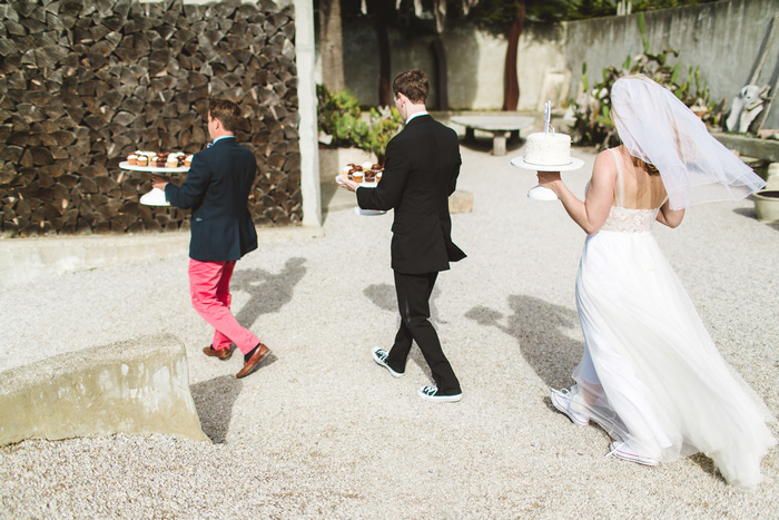 bride and groom and officiant carrying cakes